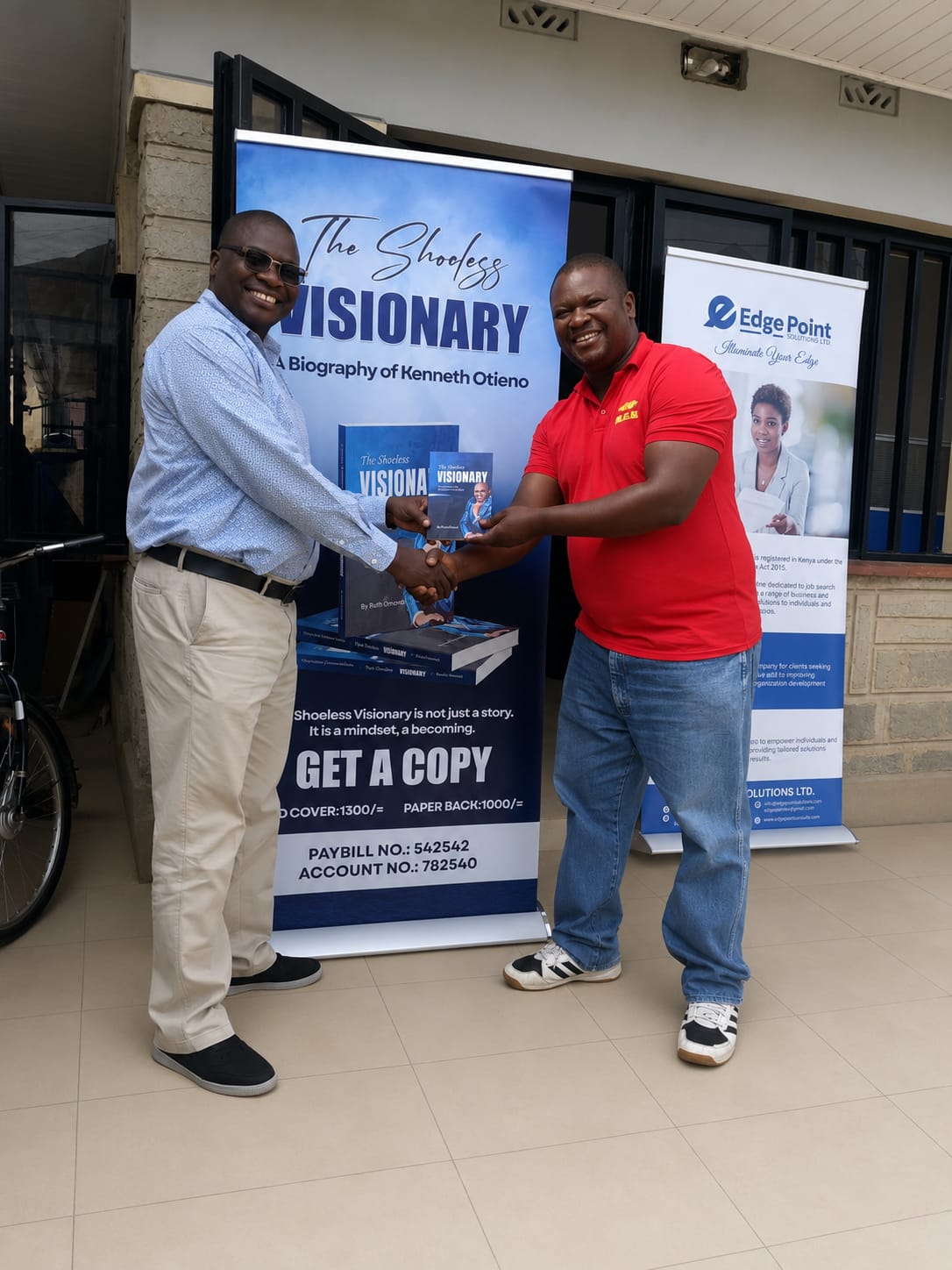 Kenneth hands over a copy of the book to Duncan Ager, his long term friend, in Kisumu office